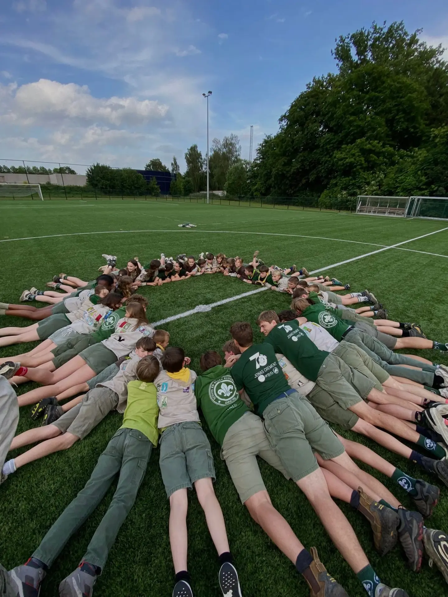 Scouts vormen samen een grote cirkel op het speelveld