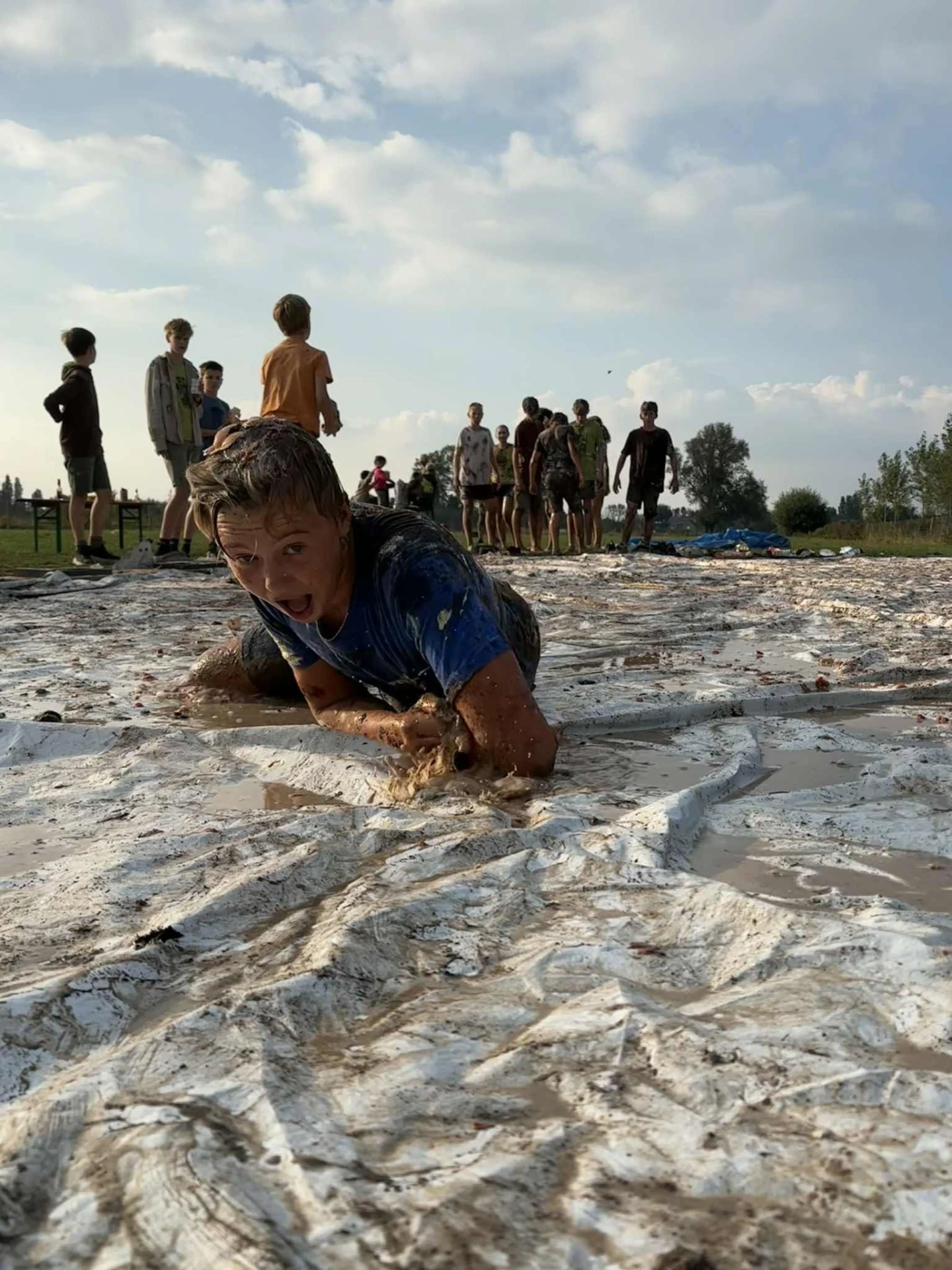 Scout doorkruist vol overgave de modderige hindernisbaan tijdens het overgangsweekend
