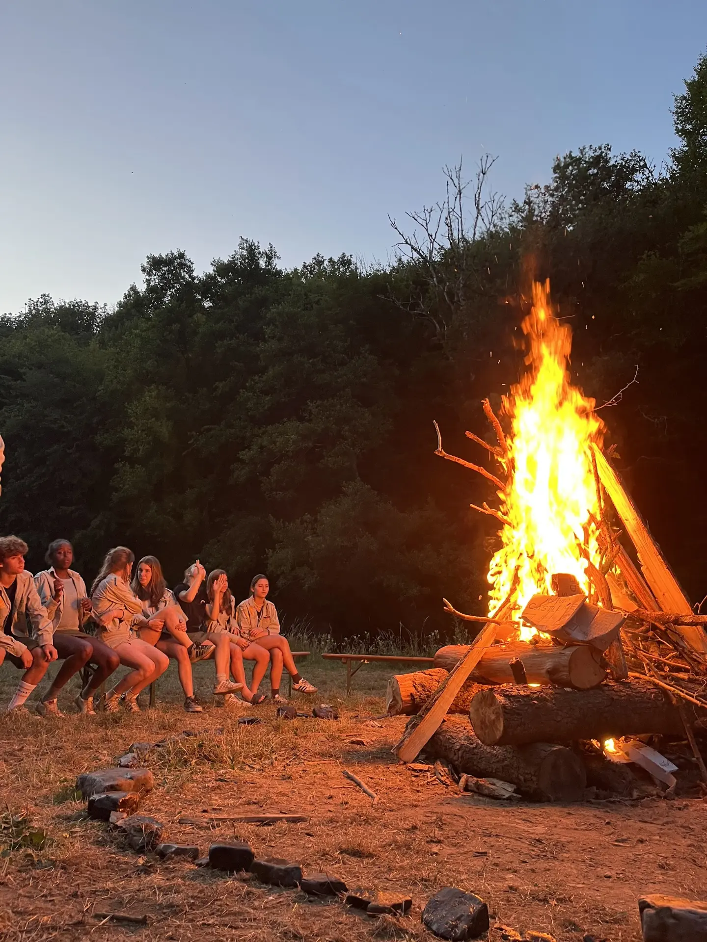 Scouts rond een groot kampvuur in de avond