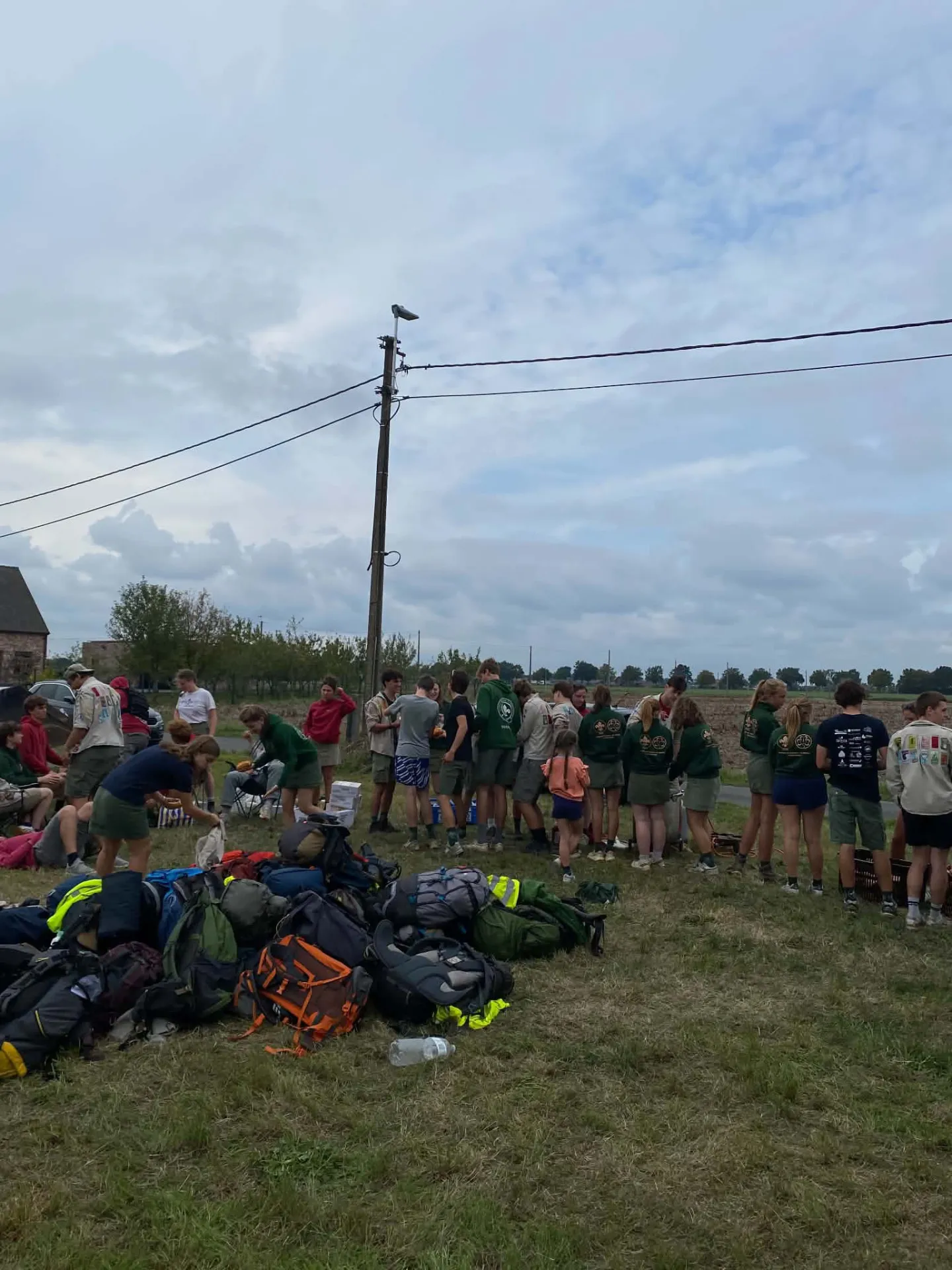 Rugzakken, leiding en scouts samen aan de kampweide
